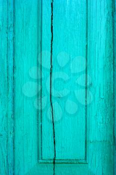 Fragment of old cracked wooden board painted in turquoise color