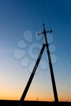 A pillar of electric transmission lines against the blue sky after sunset
