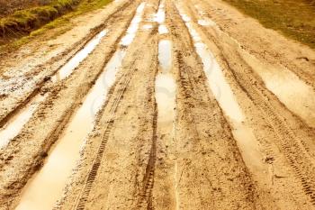Sandstone covered rural road after the rain with wheels traces filled with water