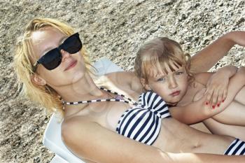 Different years two Caucasian sister girls resting on the beach