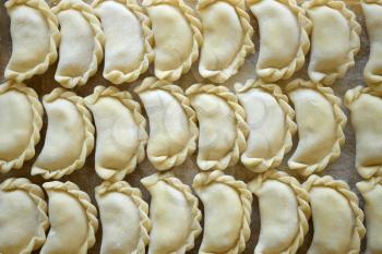 Dumplings with potatoes on the kitchen board. Dumplings with potatoes (or cottage cheese, cabbage, cherries, etc.) is a traditional Ukrainian and East Slavic kitchen dish is also known as Varenyky or 