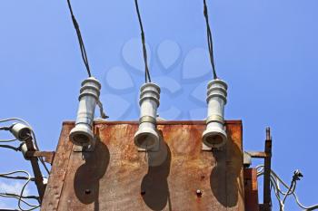 Electric insulators and wires on the old three-phase electrical transformer on a background of blue sky