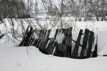 Snow-covered old village rotten fence 30104