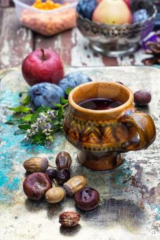 mug with herbal tea on  background of apples and plums in the autumn garden