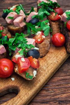 sandwiches with meat ,fresh tomatoes, onions and olives on wooden table top.Photo tinted