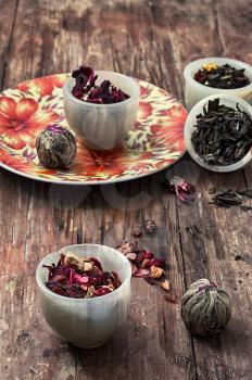 tea strainer and different varieties of tea leaves on wooden background.The toned image
