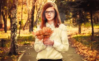 Beautiful girl in autumn Park with maple listeme in the hands
