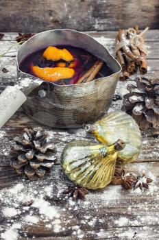 Brewed mulled wine with spices in a stylish pot and Christmas decorations