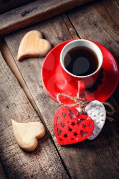 Red Cup with black coffee and two carved decorative wooden heart.Selective focus