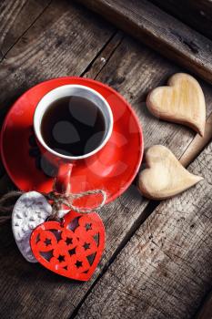 Red Cup with black coffee and two carved decorative wooden heart.Top view