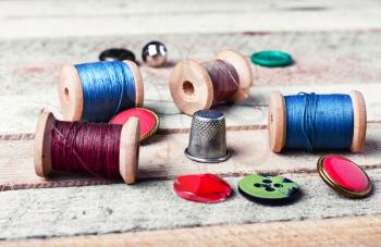 spools of thread and various buttons on wooden background