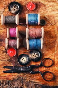 Six antiquated sewing thread and buttons on retro background