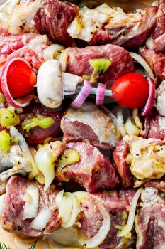 Meat in the spices and marinade with kiwi threaded on skewers for kebabs