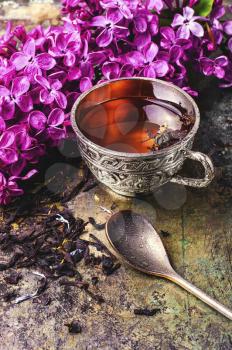 Brew tea in a stylish circle,branch of lilac on metallic background