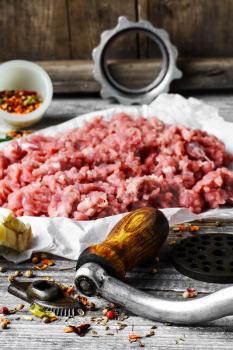 Minced meat and parts of meat grinder on wooden table in rustic style