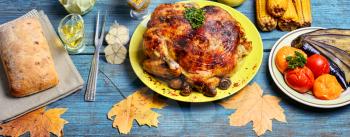 Kitchen table with baked chicken in vegetables and strewn with autumn leaves
