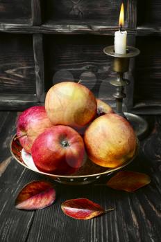Still life with autumn harvest apples and candlestick with candle