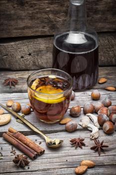 glass of mulled wine with almonds,cinnamon and anise on background of carafe of wine