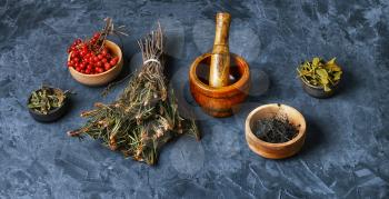 Bundle herbs and mortar with pestle on slate background