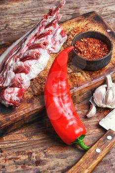 raw meat on the rib of lamb in hot spices on the kitchen board