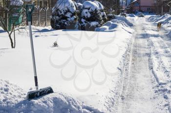 Shovel and winter snow cover street with cleared road Fresh snowdrift way. Snowy covered street. Snowflake and ice in sunlight