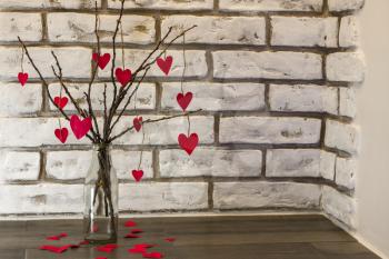Branches and fallen hearts bouquet on white brick wall background