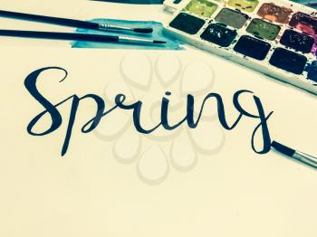 Mockup with a White Page, Word Spring, Paints and Brushes. Toned Studio Photo