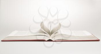 Opened book with sheets in the form of heart, studio shot