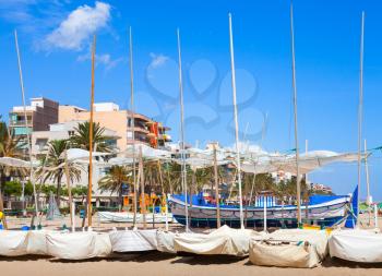 Sailing boats lay on the sandy beach in Calafell town, coast of Mediterranean sea, Catalonia, Spain