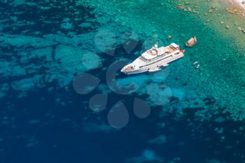 Luxury white pleasure yacht anchored near rocky coast of Corsica island, birds eye view 