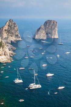 Faraglioni rocks of Capri island, Italy. Vertical coastal landscape with yachts and pleasure boats