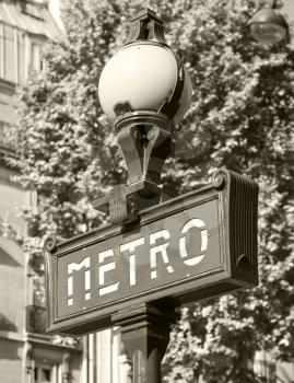 Street sign at the entrance to the Paris Metro, banner with text on the street lamp, retro stylized sepia toned photo