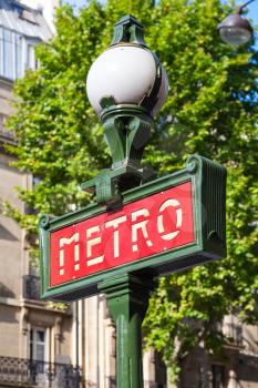 Street sign at the entrance to the Paris Metro, red banner on the street lamp