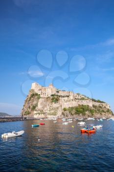 Vertical coastal landscape of Ischia port with Aragonese Castle and anchored pleasure boats