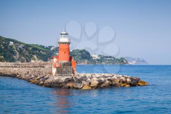 Red lighthouse tower on the breakwater. Entrance to Ischia Porto. Mediterranean sea, Italy