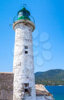 White stone lighthouse tower with green top. Entrance to Propriano port, Corsica island, France