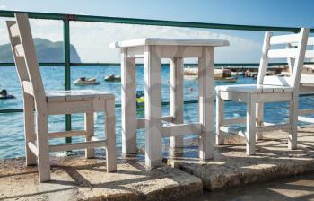 White wooden chairs and table stand on the Adriatic sea coast in Montenegro