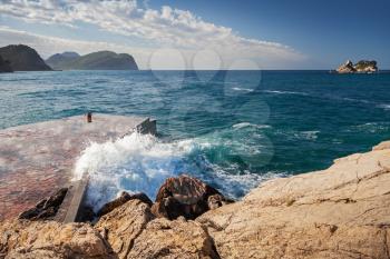Stone breakwater with breaking waves. Montenegro, Adriatic Sea