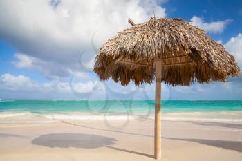 Wooden umbrella on empty sandy beach. Atlantic ocean coast, Dominican republic 