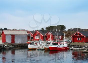 Norwegian fishing village with red wooden houses and small boats on the sea coast