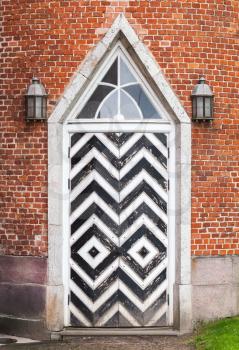 Wooden door in red brick wall, Gothic Revival architecture style. Background texture