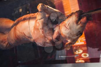 Whole pig is fried on a spit, closeup photo with selective focus