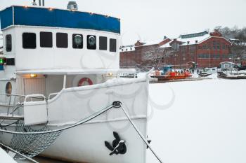 Small boat is moored near river coast. Winter in Turku town, Finland