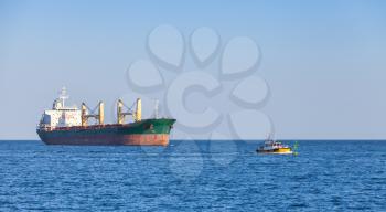 Bulk carrier. Big cargo ship sails on the Sea with small pilot boat