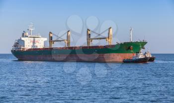 Bulk carrier and tug boats. Big cargo ship sails on the Black Sea
