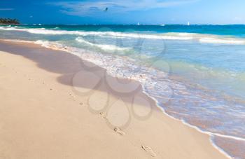 Empty sandy beach landscape with footsteps in coastal sand. Atlantic ocean coast, Dominican republic. Punta Cana