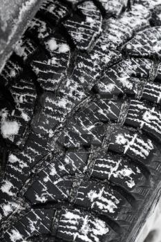 Car wheel, snow tire with metal studs, which improve traction on icy surfaces, close-up vertical photo with selective focus
