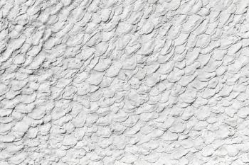 Stone wall with decorative relief white plaster pattern, background photo texture