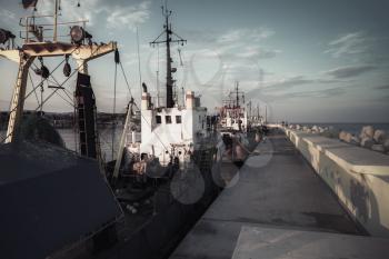 Industrial fishing boats are moored in port of Nesebar, Bulgaria. Dark vintage tonal correction filter, retro style effect