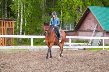 Riding lessons, teenage Caucasian girl rides a horse on outdoor manege